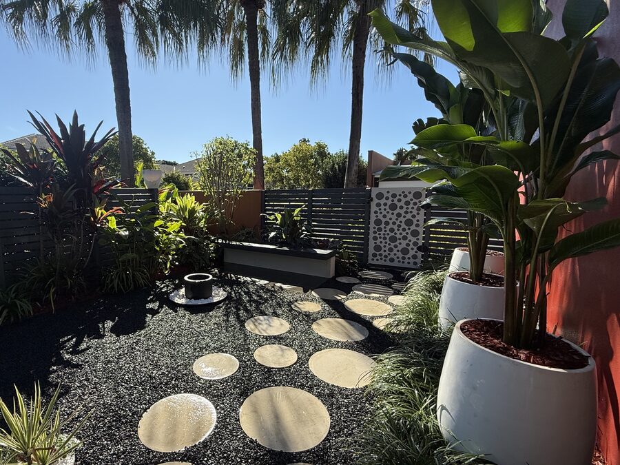 Finished landscaped courtyard with sandstone stepping stones, aluminium slat screen and established plantings